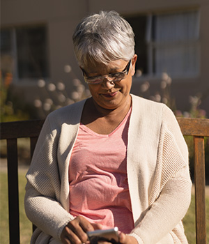 a woman sits on a bench looking at her phone